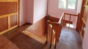 A room with a sloped ceiling, a wooden chair, a window, and a door. - Valley View Lodge & Restaurant (Panboche)