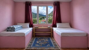 A room with two beds, a small table, and a view of a mountainous landscape. - Valley View Lodge & Restaurant (Panboche)