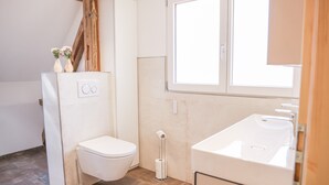 A compact bathroom with a toilet, a sink, and a window. - Apartment 'Ferienwohnung Schätzle' (Fischerbach)