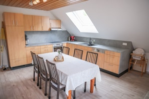 A compact kitchen with wooden cabinets, a dining table, and a skylight.
