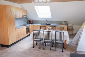 A modern kitchen with wooden cabinets, a dining table set for four, and a skylight above.