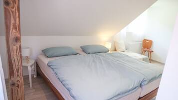Een slaapkamer met een bed, kussens, een nachtkastje, een lamp en een radiator.