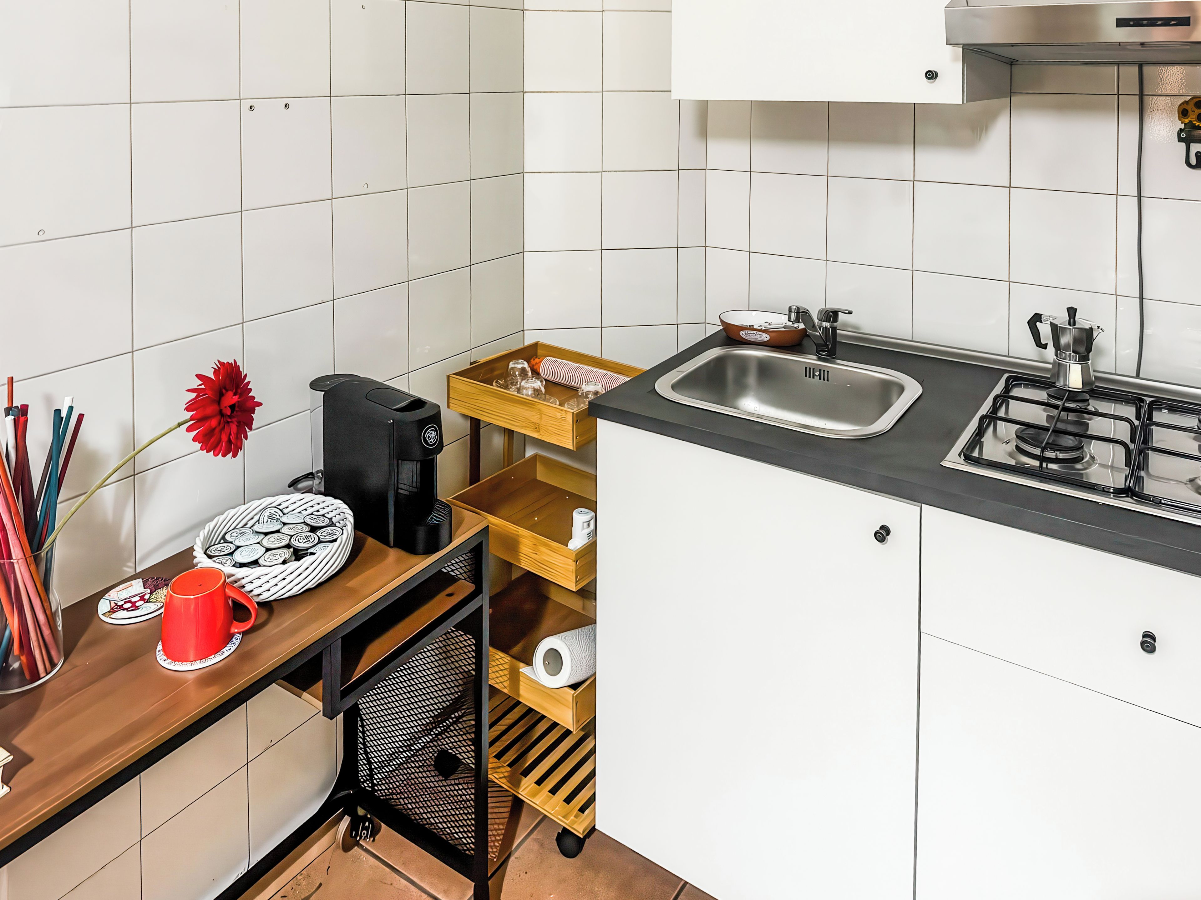 Una cocina compacta con cafetera, lavamanos y estufa.