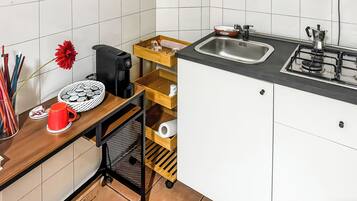Una cocina compacta con cafetera, lavamanos y estufa.