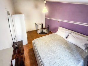 A bedroom with a bed, a desk, a chair, a small table, and a wall-mounted light fixture. - Le Dimore - Potenza. (Potenza)