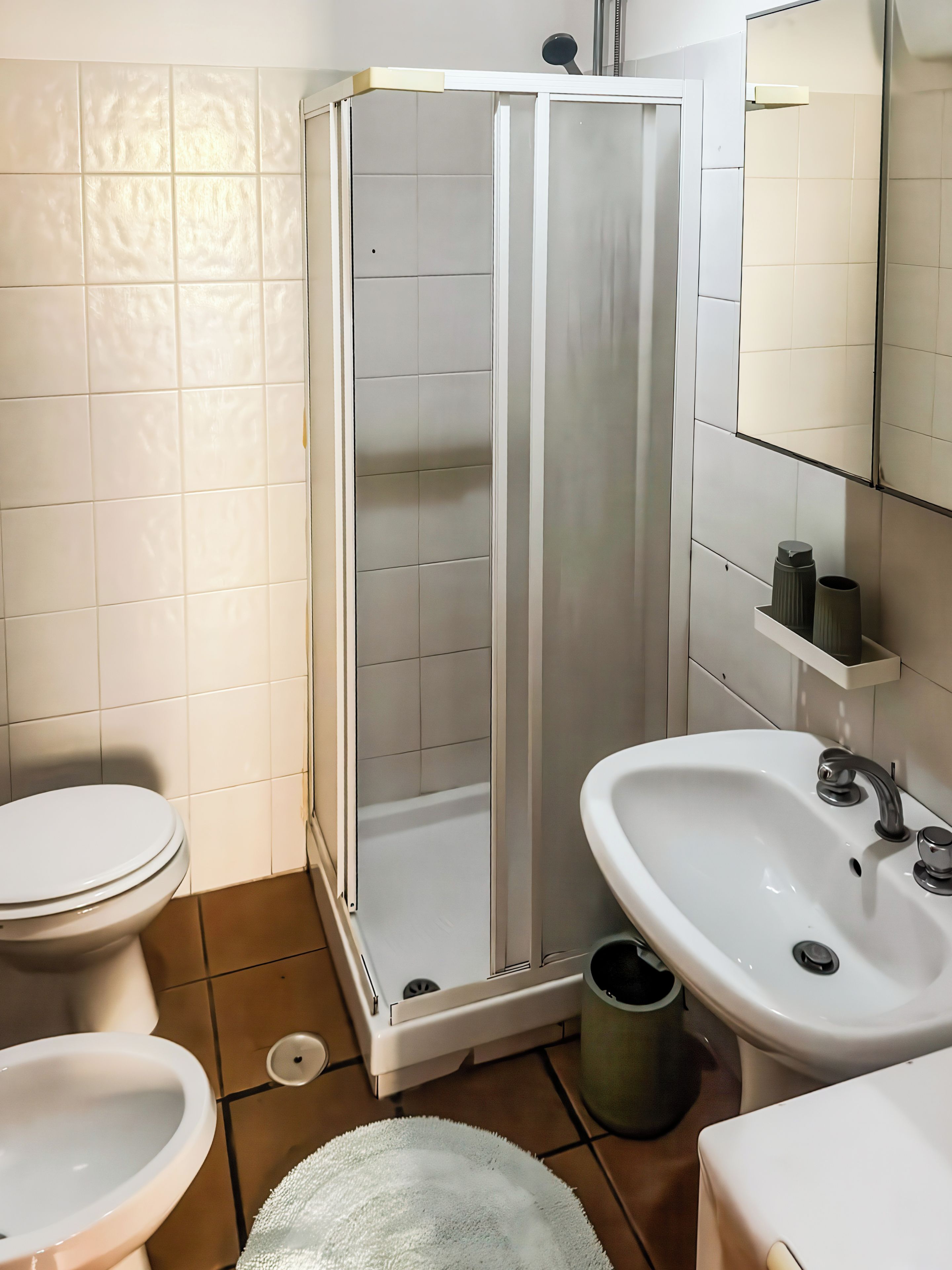 A bathroom with a toilet, sink, and shower enclosure.