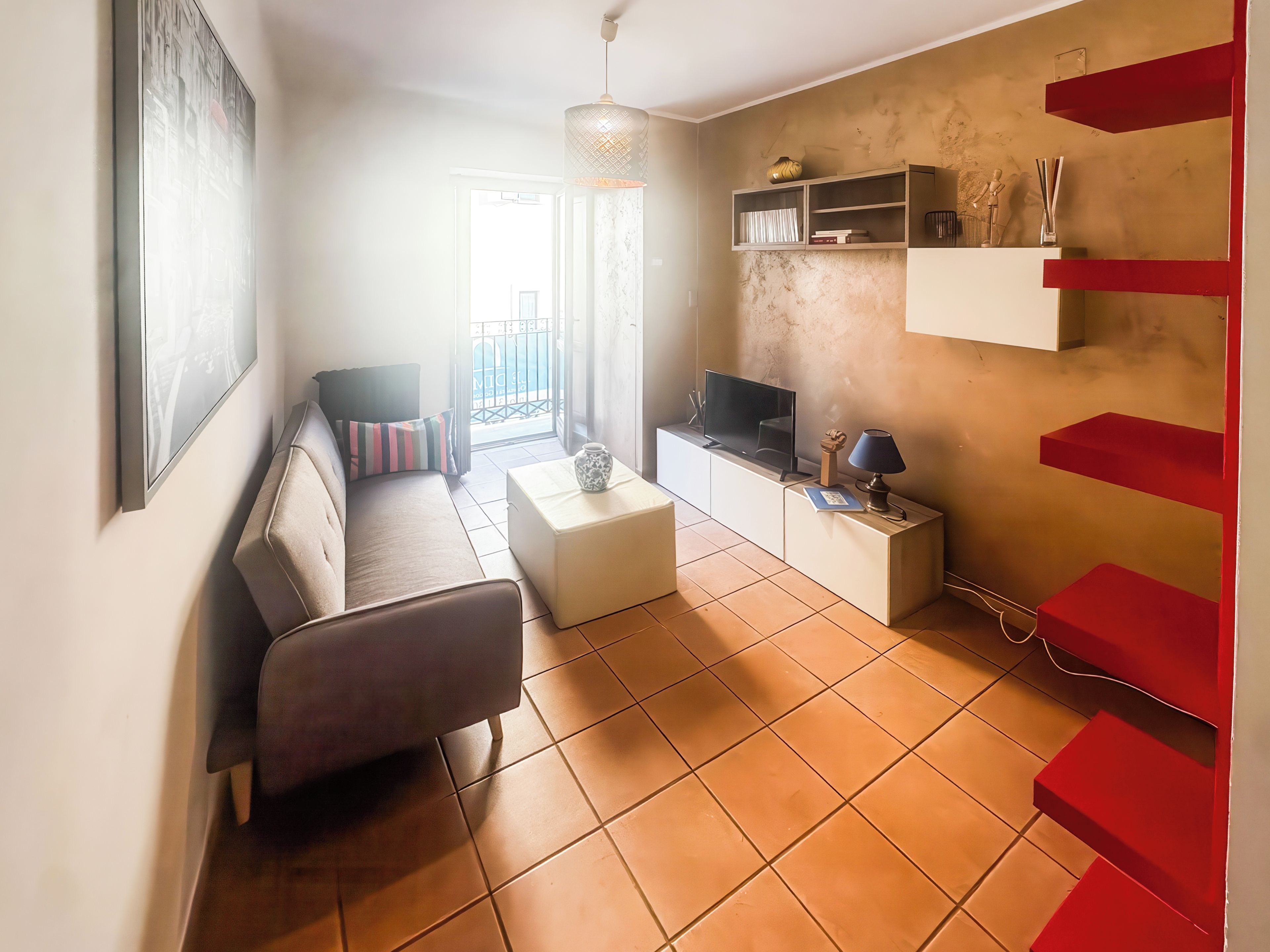 A living room with a sofa, coffee table, TV, and a red staircase.