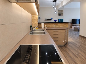 Een moderne keuken met een inbouwfornuis, een RVS-spoelbak en houten keukenkastjes.