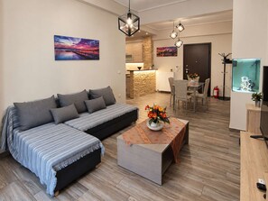 Een moderne woonkamer met een bank, een salontafel en een eethoek met stoelen.