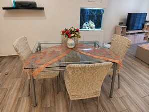 A dining table with a glass top and a woven table runner, surrounded by wicker chairs. - Zografou Two Bedroom Apartment Near Central Athens (Zografou)