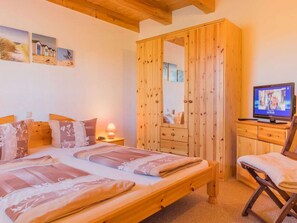 Ein Schlafzimmer mit einem hölzernen Bett, einem Schrank aus Holz, einem Fernseher und einem Stuhl.