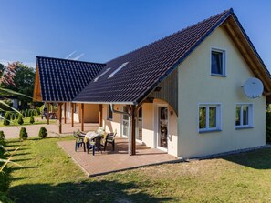 Ein zweistöckiges Haus mit überdachter Terrasse, Satellitenschüssel und gepflegtem Rasen.