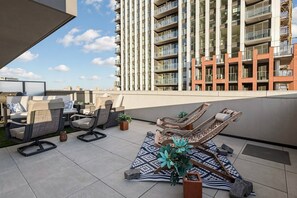 Una terraza en la azotea con sillones de descanso, un tapete estampado y plantas en macetas.