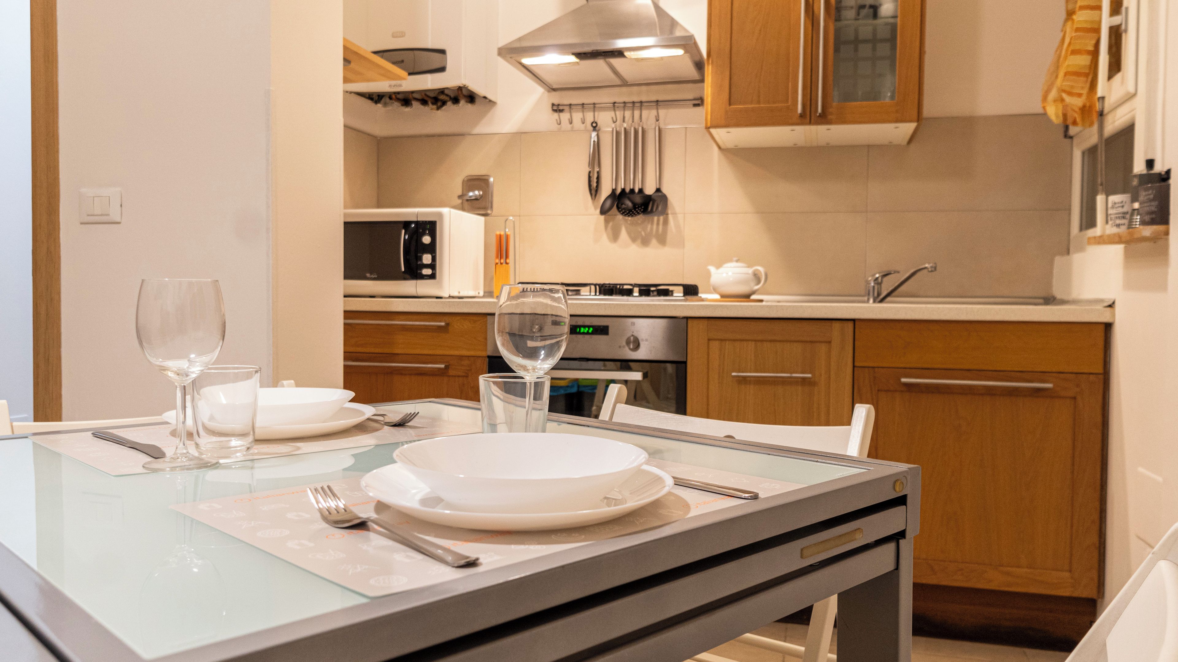 A modern kitchen with a dining area, equipped with a microwave, stove, and various utensils.