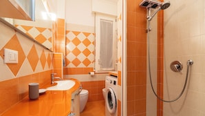 A bathroom with a shower, a sink, a toilet, and a washing machine. - Achillini 9 (Bologna)