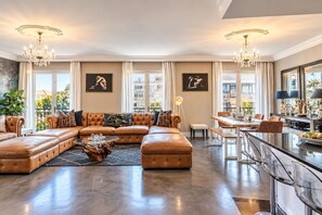 Ein geräumiges Wohnzimmer mit einer großen Eckcouch, einem Essbereich und einer Küche mit Barhocker.