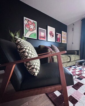 A modern living room with a black leather chair, a wooden coffee table, and a patterned rug. - Modern, stylish house in Anfield (an Áit Bheag) (Liverpool)