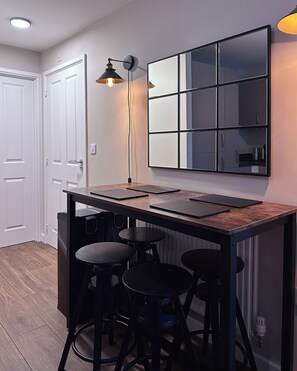 A compact kitchen with a wooden countertop, three stools, a hanging light fixture, and a large mirror. - Modern, stylish house in Anfield (an Áit Bheag) (Liverpool)