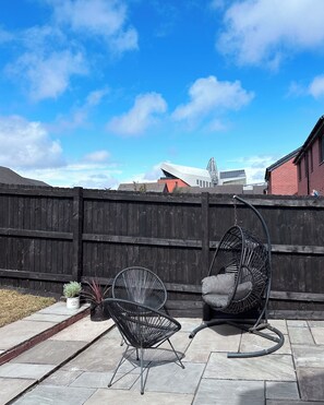 A patio with two black metal chairs, a hanging chair, and a potted plant. - Modern, stylish house in Anfield (an Áit Bheag) (Liverpool)