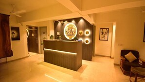 Un'area della reception di un hotel, con una scrivania, una ventola a soffitto e opere d'arte incorniciate alle pareti.