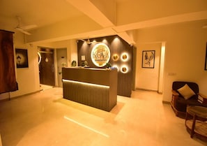 A hotel reception area with a reception desk, a ceiling fan, and framed artwork on the walls. - Hotel Aura Nr Kokilaben Hospital (Mumbai)