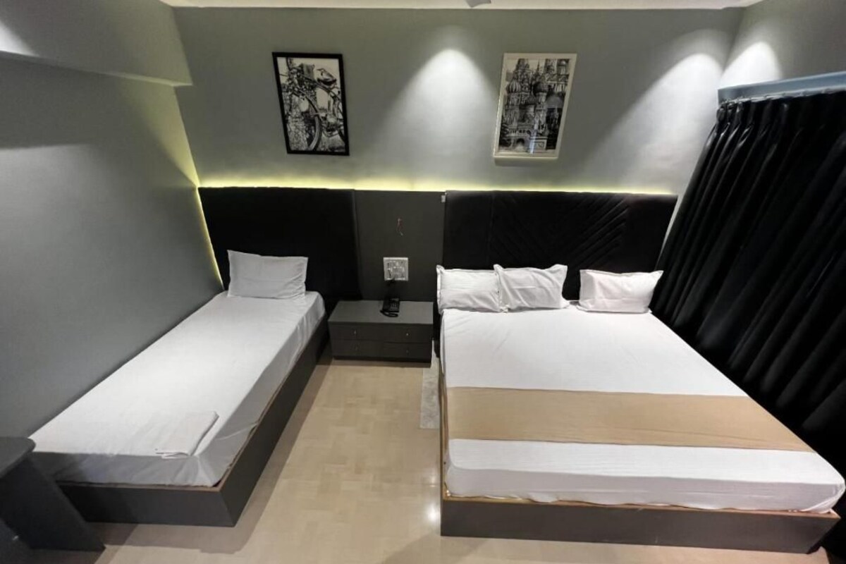 A hotel room with two single beds, a nightstand, and two wall-mounted light fixtures.