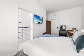 A hotel room with a bed, a TV, a desk, and a shower area. - Collins Ave Shopping nearby! Junior Queen South Beach Studio (Miami Beach)