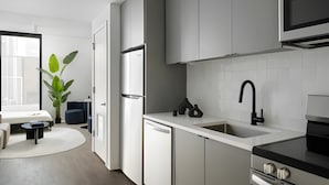 A modern kitchen with white cabinetry, a black faucet, and a built-in oven. - Miles at Ybor - Tampa (Tampa)