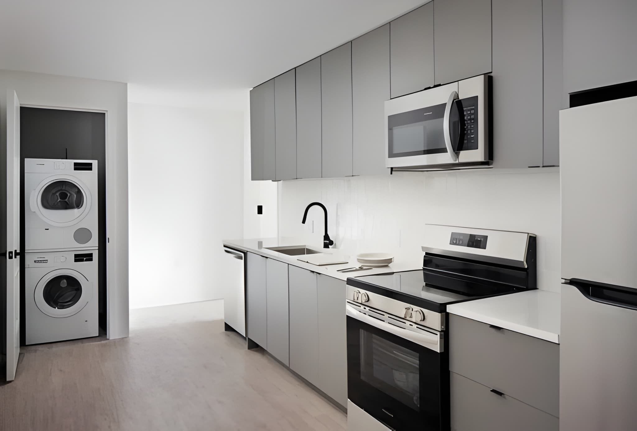A modern kitchen with a built-in washer, a microwave, a sink, and a stove.