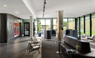 Eine moderne Lobby mit Sitzbereichen, einer großen Säule und Kunstwerken an den Wänden.