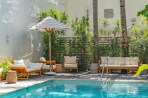 A poolside area with lounge chairs, a pool, and tropical plants. - Conventions Ctr & Collins Ave is nearby, Junior King Studio (Miami Beach)