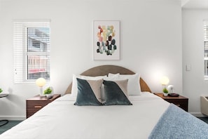 A bedroom with a large bed, two bedside tables with lamps, a wall-mounted abstract art piece, and a window with blinds. - Free On the Go Breakfast Onsite, near Collins Ave Studio (Miami Beach)
