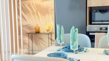 A modern dining area with a table set for two, featuring blue plates and glassware.