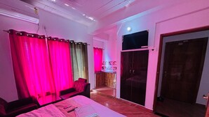 Une chambre à coucher avec un lit, des rideaux, un téléviseur et une armoire.