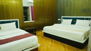 Une chambre d’hôtel avec deux lits, une fenêtre, un miroir et un plancher en bois.
