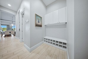 Um interior moderno com um corredor que leva a uma sala de jantar, uma parede branca com uma obra de arte emoldurada e armários embutidos.