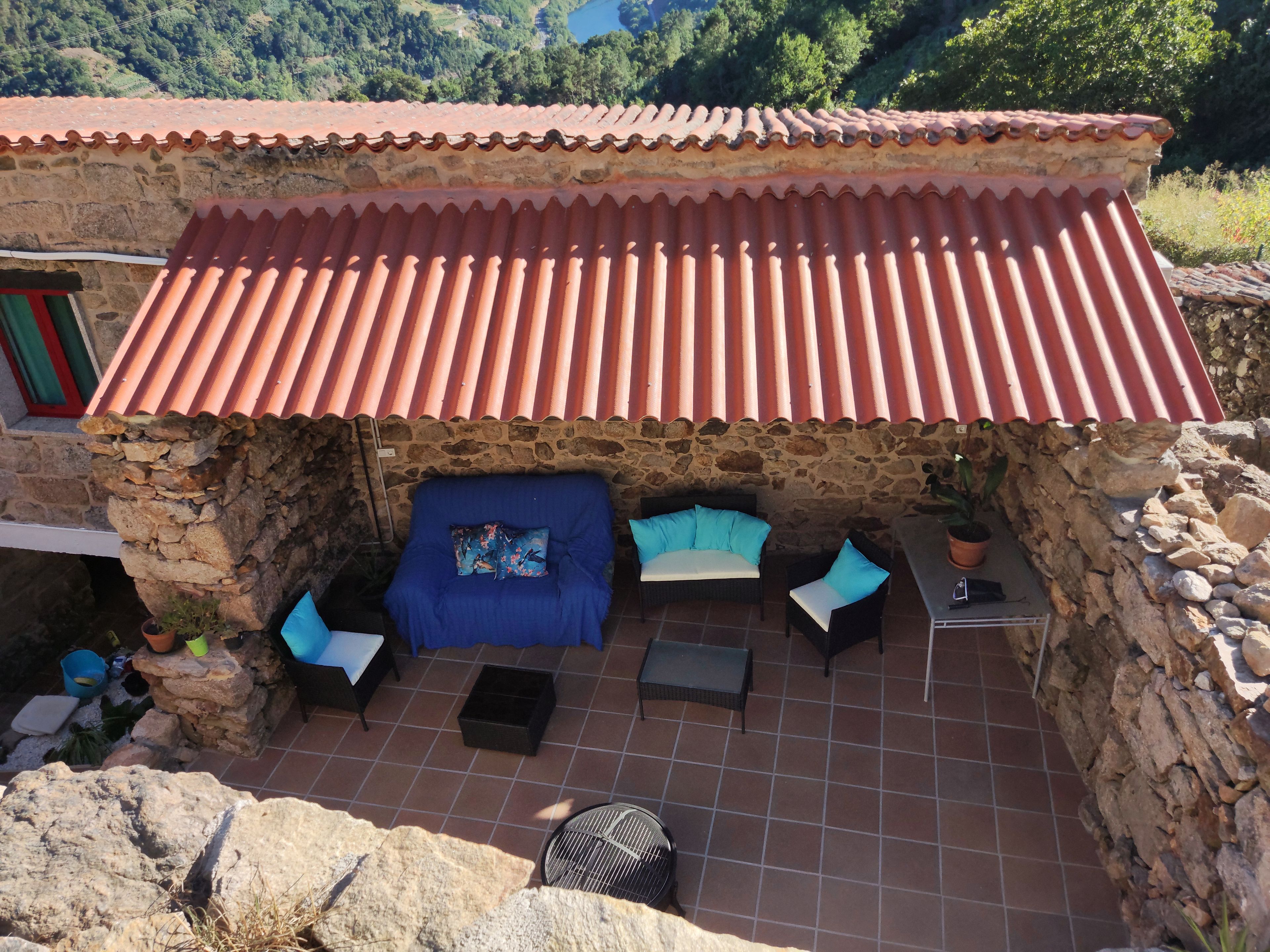 A stone building with a tiled roof, a blue sofa set, and a small table.