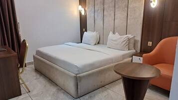 Une chambre à coucher avec un lit, une table ronde, une chaise orange et un climatiseur fixé au mur.