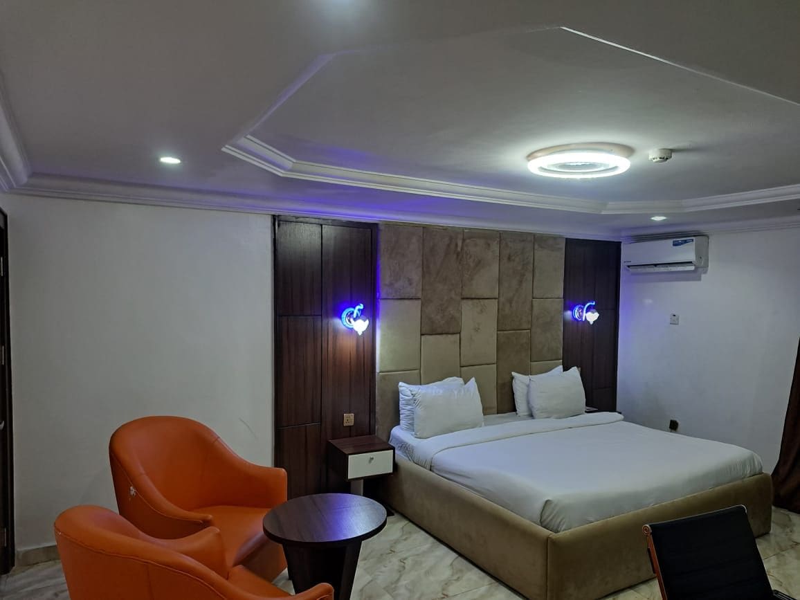 Habitación de hotel con cama, una silla, una mesita y aire acondicionado de pared.