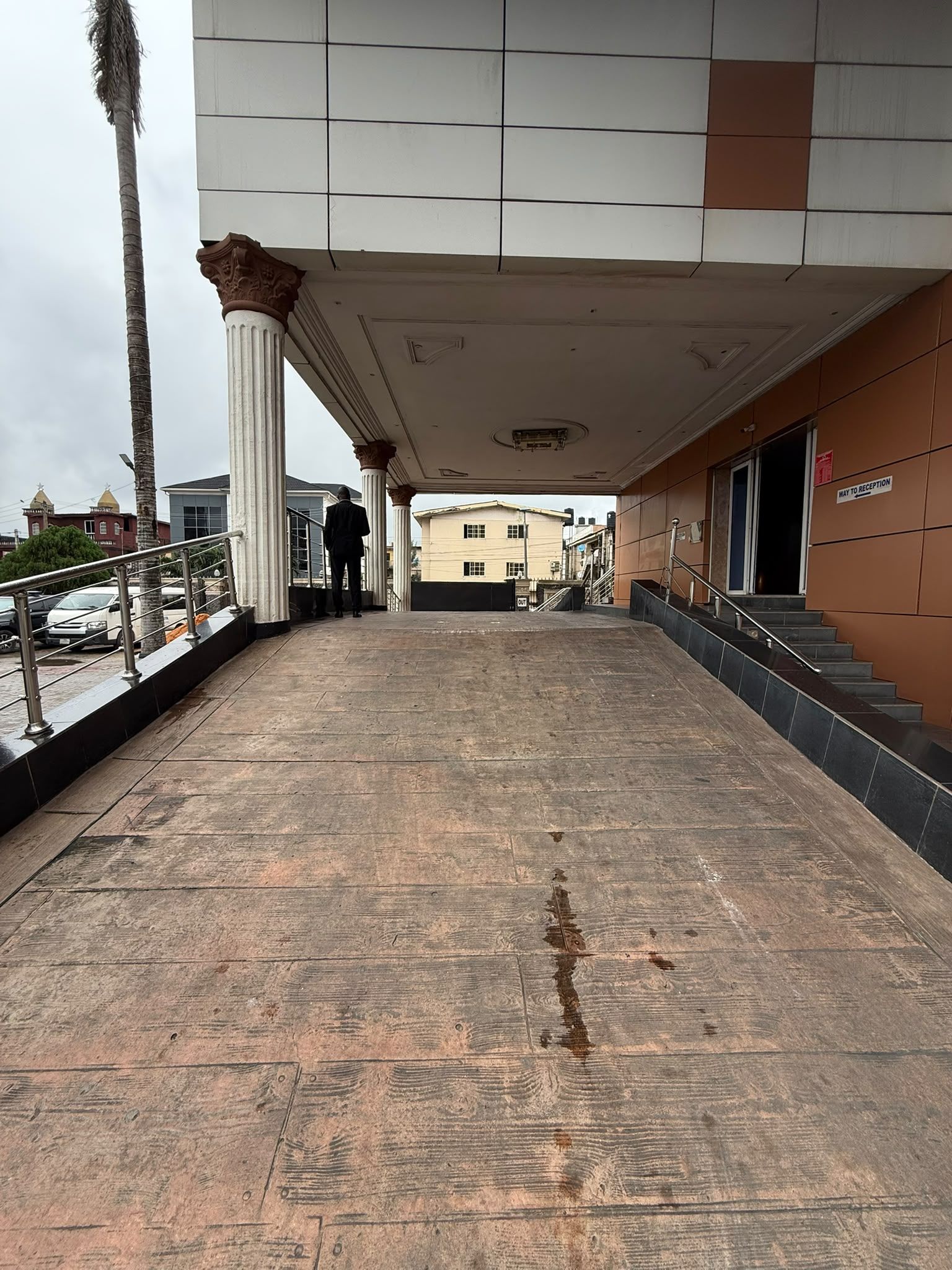 A covered walkway with a tiled floor leading to a building entrance.