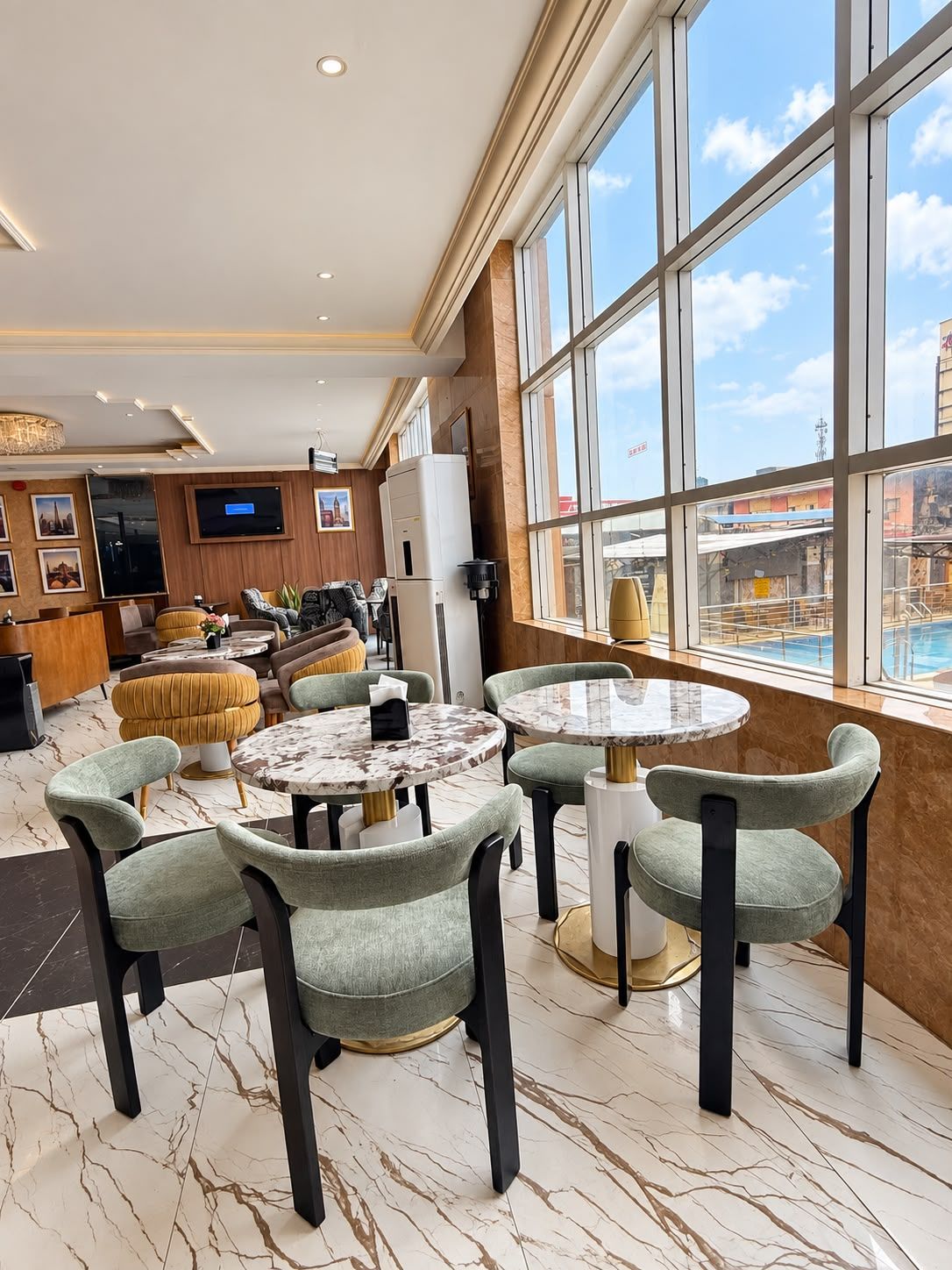 A hotel lobby with a pool view, marble flooring, and modern furniture.