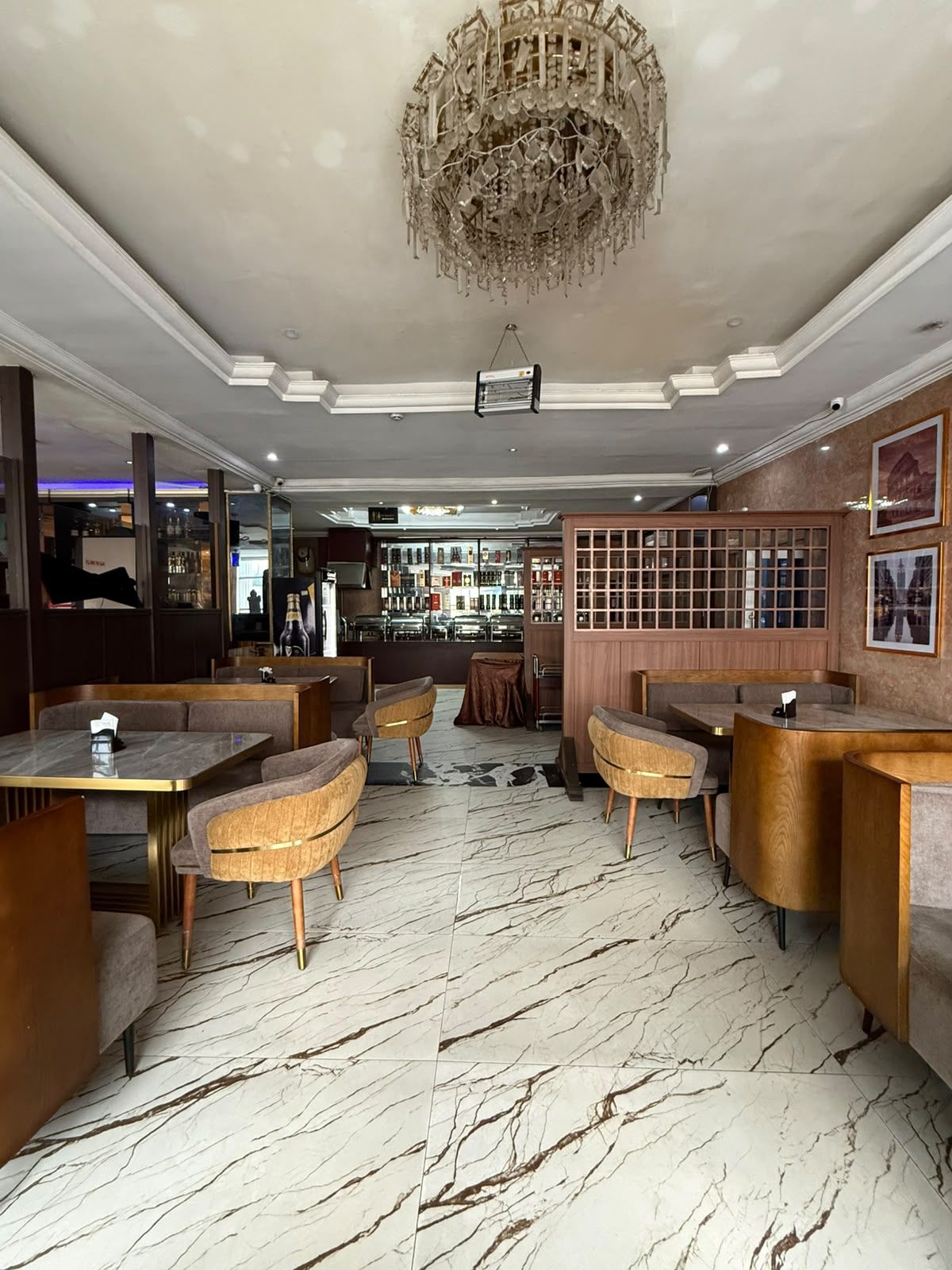 L’intérieur d’un restaurant avec un sol en marbre, des sièges rembourrés, un lustre et un coin bar.