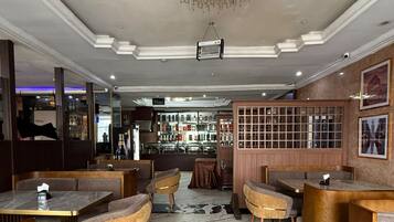 L’intérieur d’un restaurant avec un sol en marbre, des sièges rembourrés, un lustre et un coin bar.