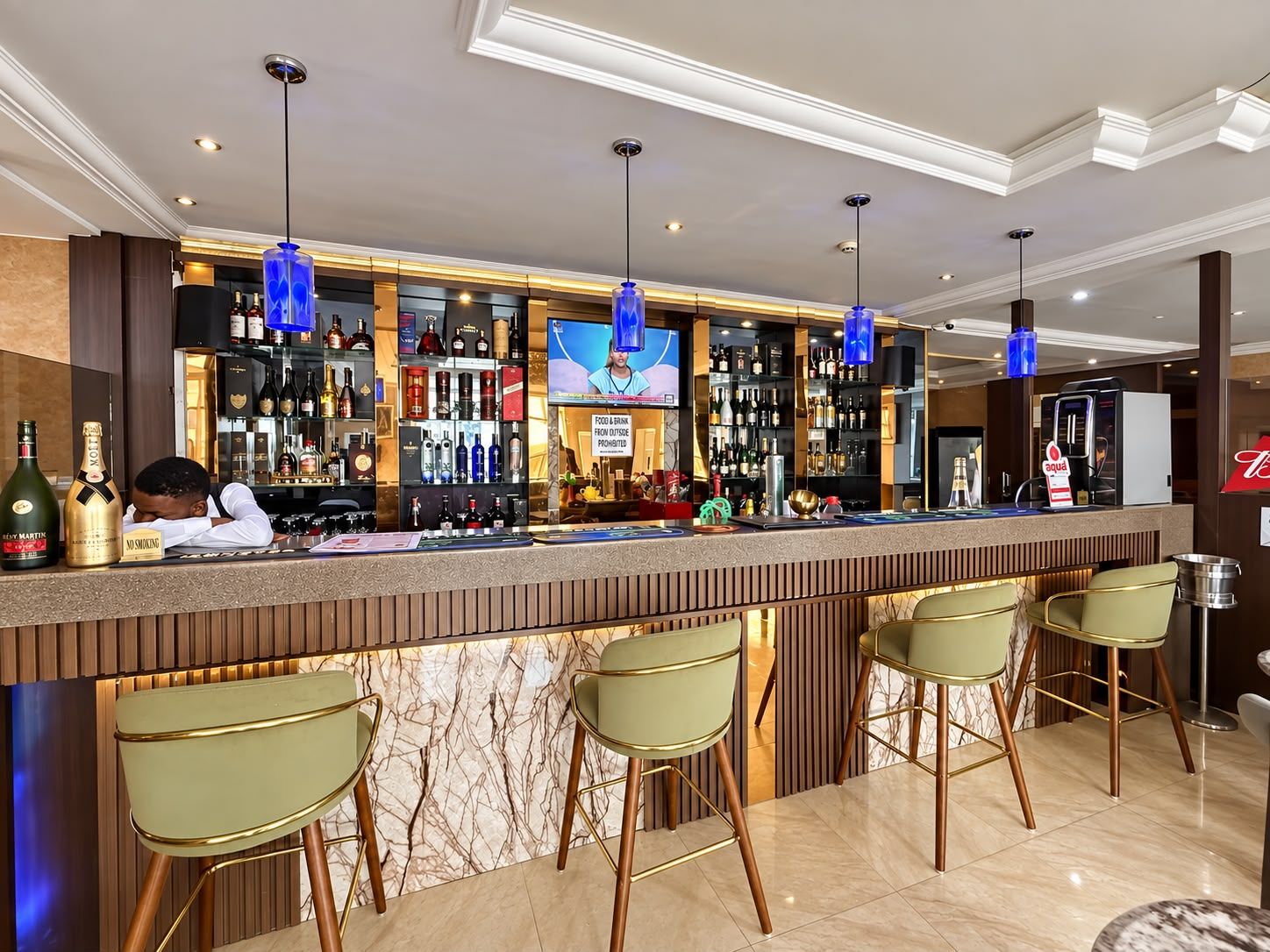 A bar area with a marble countertop, multiple liquor bottles, and bar stools.