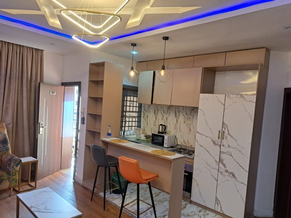 A compact living space with a kitchenette, a dining area with bar stools, and a sofa.