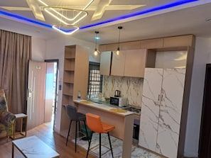 A compact living space with a kitchenette, a dining area with bar stools, and a sofa. - R and A City Hotel  (Lagos)