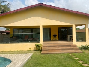 A yellow building with a red roof, large windows, and a wooden staircase leading to a covered porch.
