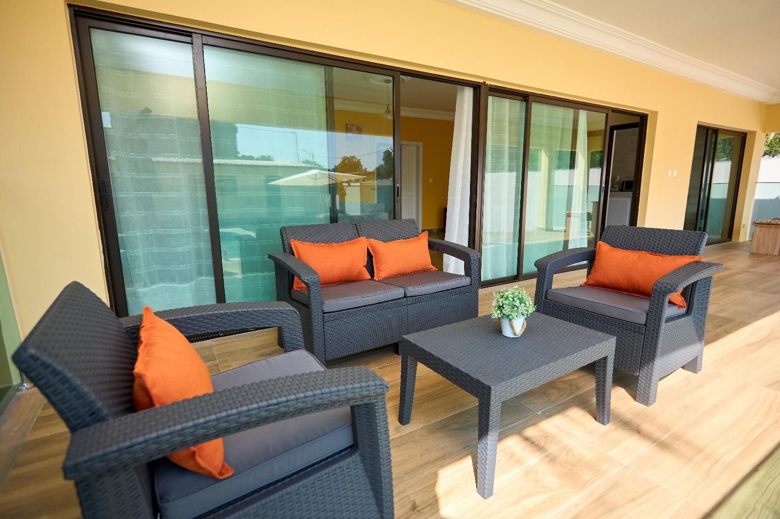A balcony with wicker furniture, including two sofas and a table, and a potted plant.