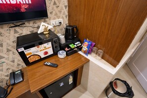 Uma cozinha compacta equipada com micro-ondas, máquina de café, lanches e controle remoto.