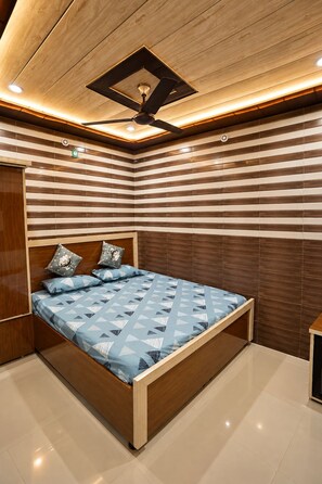 Quarto moderno com cama de madeira, azulejos listrados na parede e ventilador de teto.